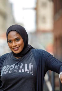 a woman wearing a hijab is leaning against a railing