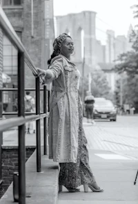 a black and white photo of a woman leaning on a railing