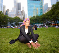 a woman in a hijab sitting on the grass in a park