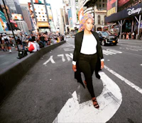 a woman wearing a hijab crossing the street in times square